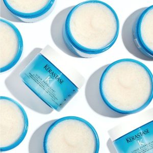 Blue jars of Kerastase K Scrub Energisant exfoliating scrub arranged on a white surface